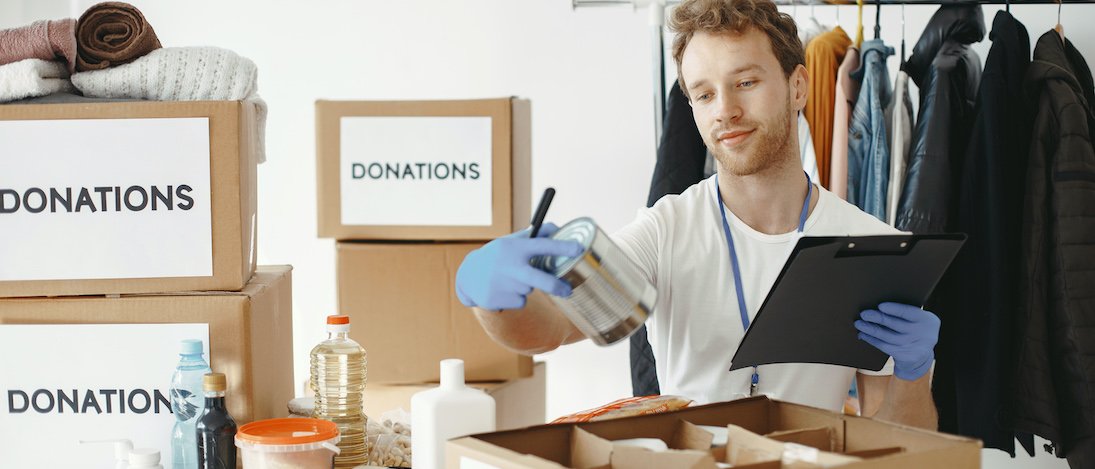 volunteer-collects-things-from-donations-guy-packs-boxes-with-things-man-compares-endowment